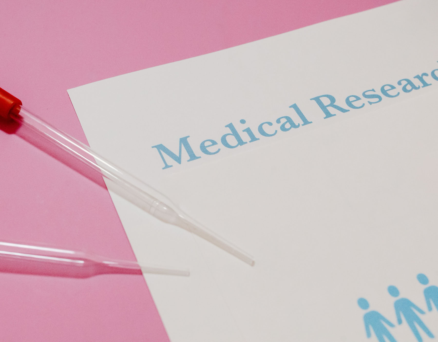 Close-up of a medical research document and pipette on a pink surface, highlighting scientific research and healthcare.